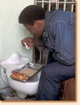 Prisoner eating on toilet in cell